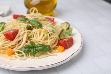 Delicious pasta primavera with tomatoes, basil and broccoli on white tiled table, closeup. Space for text