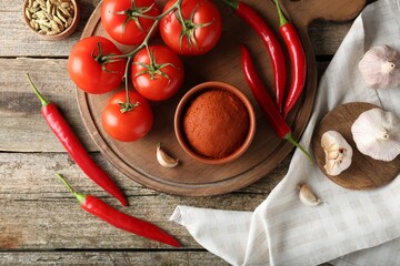 Red curry paste in bowl and ingredients on wooden table, flat lay
