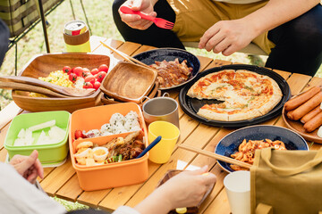 キャンプ場でバーベキュー・キャンプ飯を食べる家族（アウトドア・旅行・レジャー・ピクニック）

