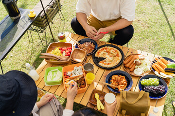 キャンプ場でバーベキュー・キャンプ飯を食べる家族（アウトドア・旅行・レジャー・ピクニック）
