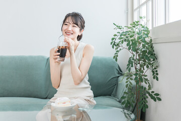 家でおやつ・間食の時間にアイスコーヒーを飲む女性
