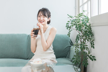 家でおやつ・間食の時間にアイスコーヒーを飲む女性
