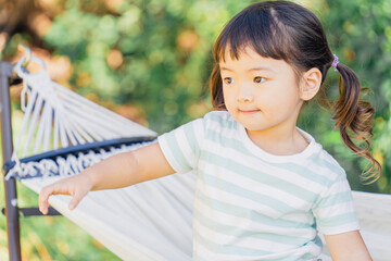 アウトドア・キャンプ場でハンモックに乗る子供（外遊び）
