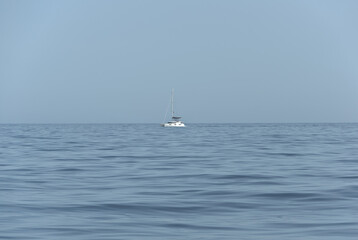 A serene image with a blue sky, sparkling sea, and a majestic sailboat sailing gracefully amidst...