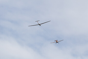 yellow plane towing a glider on a cloudy day