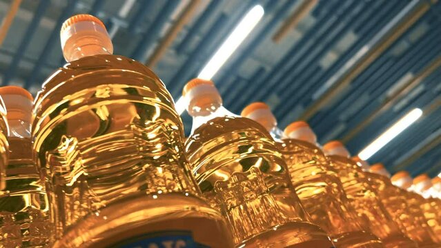 Sunflower or corn oil in plastic bottles on the shelf in a supermarket or a warehouse. Closeup shot. Bottom up view