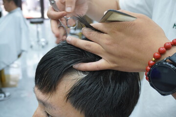 Close-up master hairdresser does hairstyle and style with scissors and comb. Concept Barbershop.