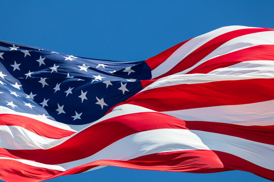 Closeup of American flag blowing in the wind with blue sky