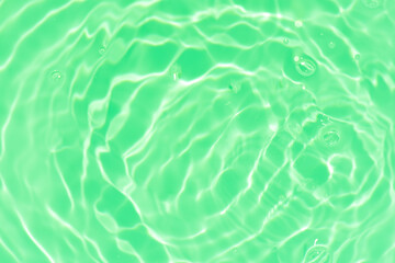 Green water with ripples on the surface. Defocus blurred transparent blue colored clear calm water surface texture with splashes and bubbles. Water waves with shining pattern texture background.