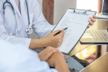 Doctor hand holding pen and explained examination results to the patient man, healthcare and medical checkup concept