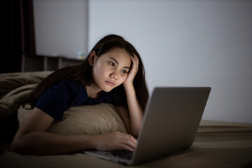 Young asian women work late at night stressed out. Tired and exhausted from working on computer laptop in the bedroom.