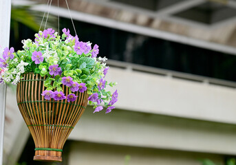 Multi-colored of fake flowers in the wooden basket  in the park with natural background at Thailand for design and decoration.