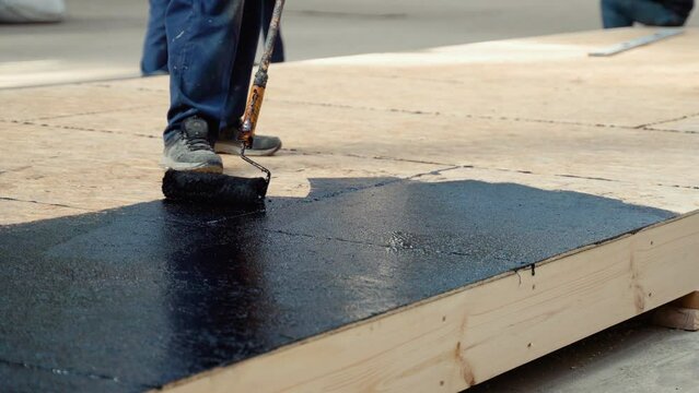 Applying hot resin to the floor for waterproofing, roller and bucket of resin, black and liquid resin. Modular prefabricated houses concept