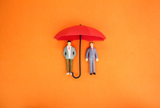 two miniature people under an umbrella. Insurance cover concept. the concept of personal protection