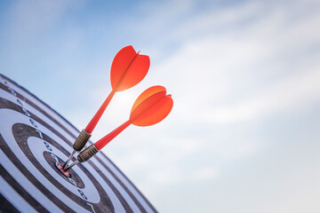 Close up shot red darts arrows in the target  of dartboard center on dark blue sky background....