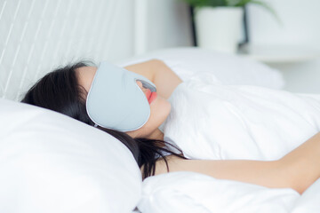 Beautiful young asian woman wearing cover eye and sleeping on bed with head on pillow comfort and happiness in the bedroom at home, girl with relax and leisure for wellness, lifestyles concept.