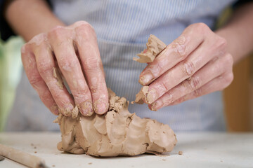 Closeup hands of ceramic artist wedging clay in art studio