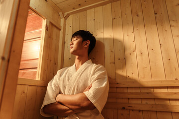 Relaxation Asian man in bathrobe sitting relaxing in the sauna. Young man healthcare and spa...