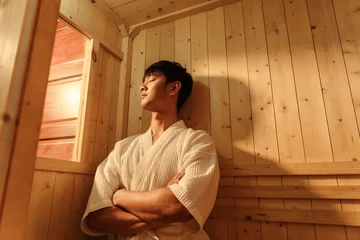 Papier Peint Lavable Spa Relaxation Asian man in bathrobe sitting relaxing in the sauna. Young man healthcare and spa treatment concept.