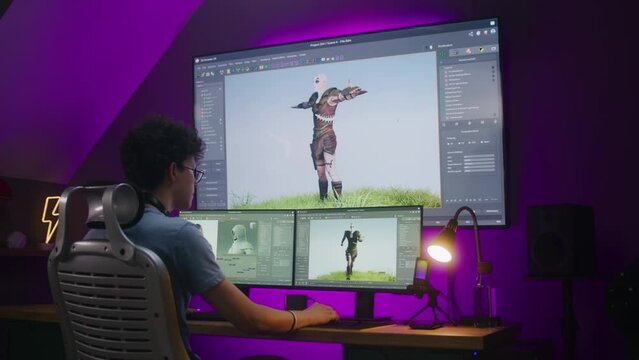 Young 3D designer draws video game character, creates animation, works remotely at home office. Computer and big digital screen with professional software interface for 3D modeling and design.