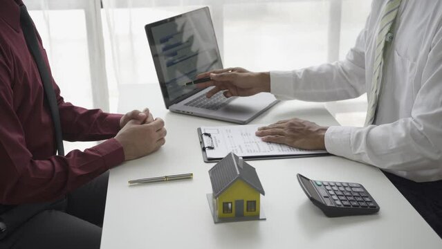 Homebuyers meet and negotiate with a real estate agent about renting or buying a home and the terms of the home purchase agreement and ask the client to sign paperwork to complete the sale.