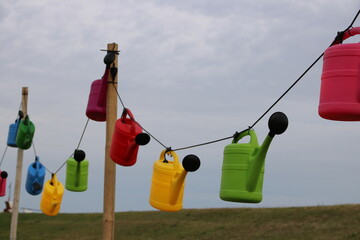 Dekoration bunte Gießkannen hängen an einer Leine hinter dem Deich an der Nordsee in Cuxhaven