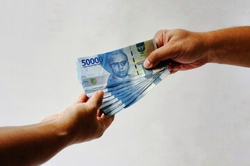 Hand holding fifty thousand rupiah note isolated on white background. Indonesian rupiah currency....