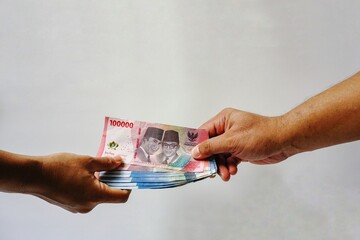 Hand holding rupiah note isolated on white background. Indonesian rupiah currency. Hand holding rupiah Indonesian money. Payment, payroll or finance concept. 