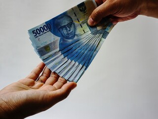 Hand holding fifty thousand rupiah note isolated on white background. Indonesian rupiah currency....