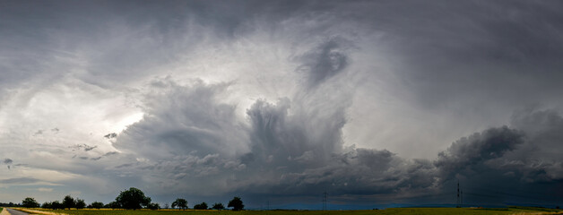 Panoramaansicht eines über das Land ziehenden schweren Unwetters mit grauem, bedeckten Himmel und Feldern im Vordergrund