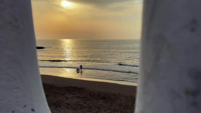 Woman walking on the beach in the sunrise. Cala La Mosca in Playa Flamenca, Orihuela Costa, Costa Blanca, Spain.