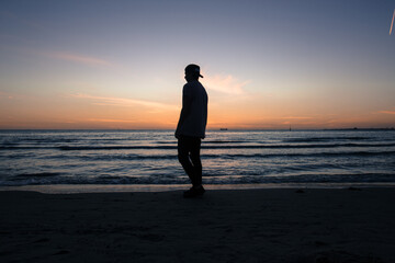 person walking on the beach at sunset