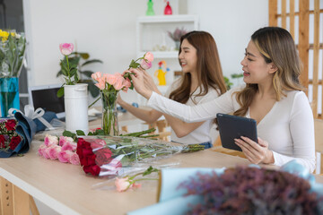 The two Asian woman florist working flower arrangement of colorful of rose to making of bouquet in flower shop.