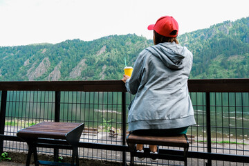 Female traveler in red hat sitting bench and looking at a beautiful mountain,sky field and nature view. Sit back.