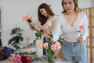The two Asian woman florist working flower arrangement of colorful of rose to making of bouquet in flower shop.