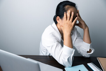 A business office worker is an asian woman is sitting in front of the laptop computer. A businesswoman stressing her body part fingers, hands arm. A femaleOffice manager is exhausted at her workplace.
