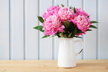 A bouquet of pink peonies on a wooden table.