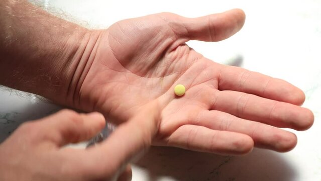 yellow pill from a blister in the palm of a person.