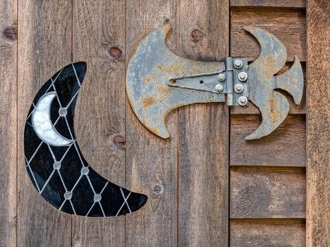 A gothic metal hinge and crescent moon design on an old wood door