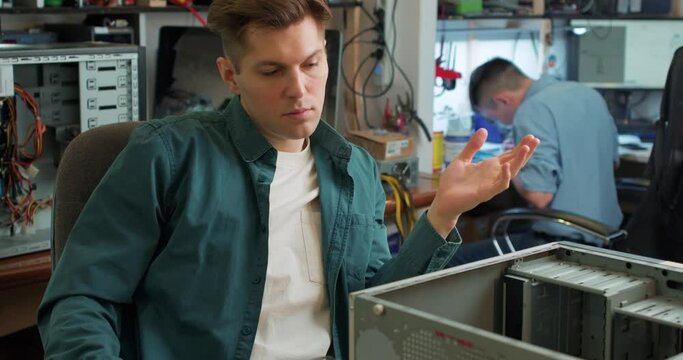pensive thoughtful serious puzzled repairman looking at disassembled computer system unit Slow motion, man does not know how to repair computer,he cannot solve problem with computer