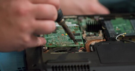 male engineer is focused on repairing electronic circuit board with soldering iron. Man hands soldiers computer circuit board using soldering iron. Slow motion close up cropped view. computer
