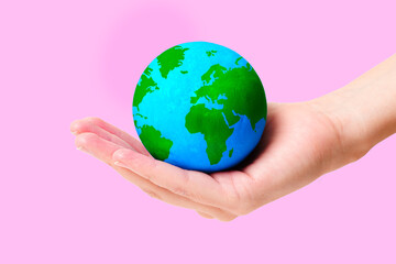 Green and Blue Globe Model in Hand Isolated on Pink