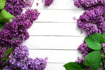 Flower frame for text with bouquets of purple lilacs on a white wooden table with space for text in the center, without anybody.