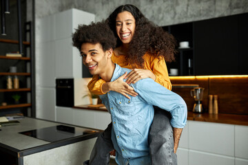 Youthful siblings having fun after long time not seeing each other, afro guy piggy-backing...