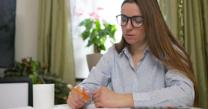 Woman sit at desk with paper bills, feeling stressed about bank loan payments