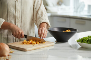 Closeup image of woman cutting pumpkin when cooking soup for dinner