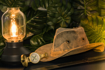 old travel hat, machete, compass, stylish lamp among the thicket of jungle leaves, Travel concept, off the beaten track, exploring new places