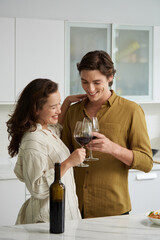 Joyful young couple in love enjoying red wine before dinner
