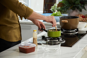 Cropped image of man cooking dinner at kitchen stove