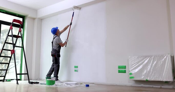 Man master paint ceiling with white paint roller in room. Wall and ceiling repair and painting
